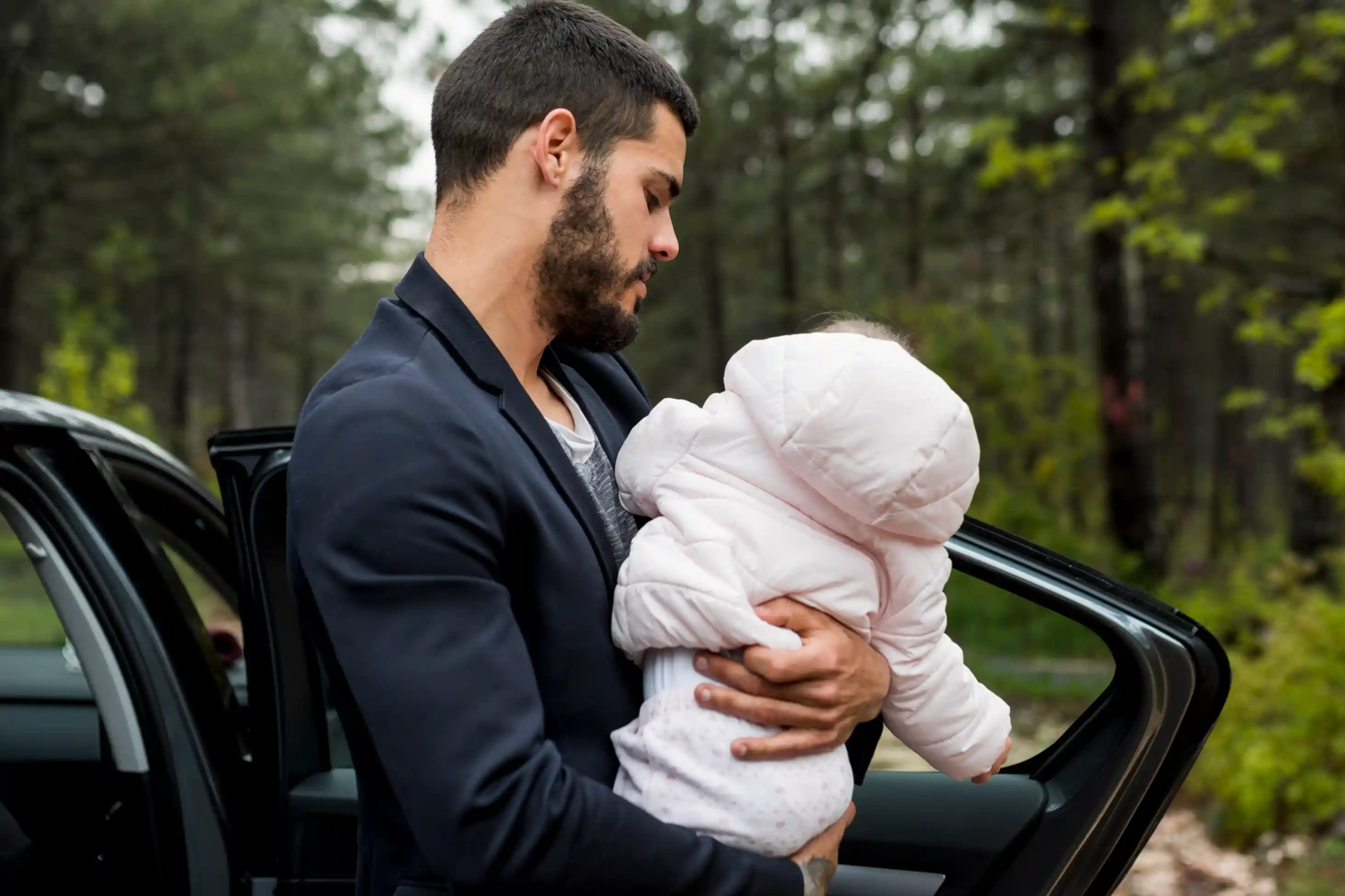 Un père tenant délicatement son bébé en sortant de la voiture après un trajet sûr et confortable
