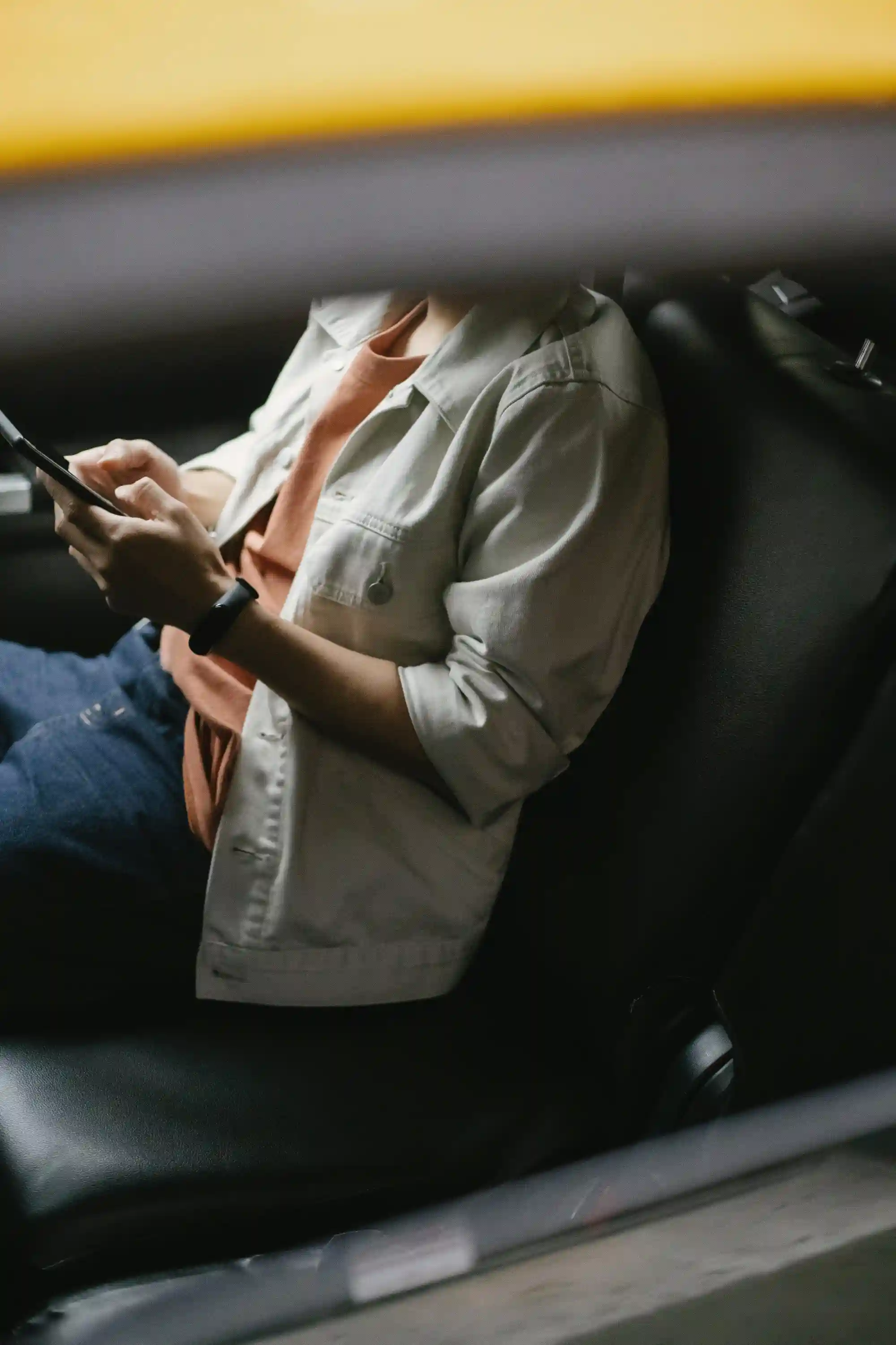 Une personne confortablement installée dans une voiture, utilisant une application de réservation de trajet sur son smartphone pour vérifier le prix avant de commencer son trajet